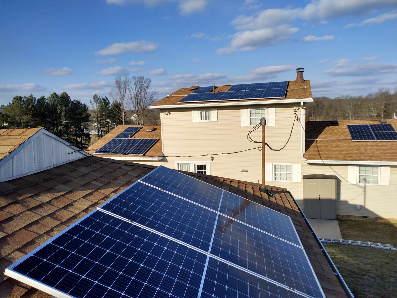 Aerial view of solar panels across several roof sections of a home