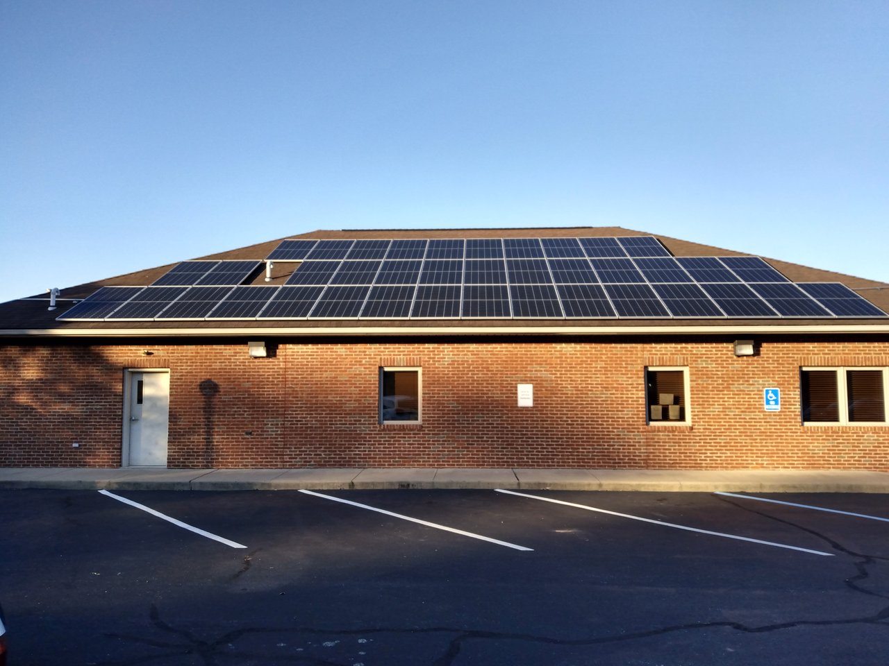 Solar panels on the low-slope roof of a brick commercial building