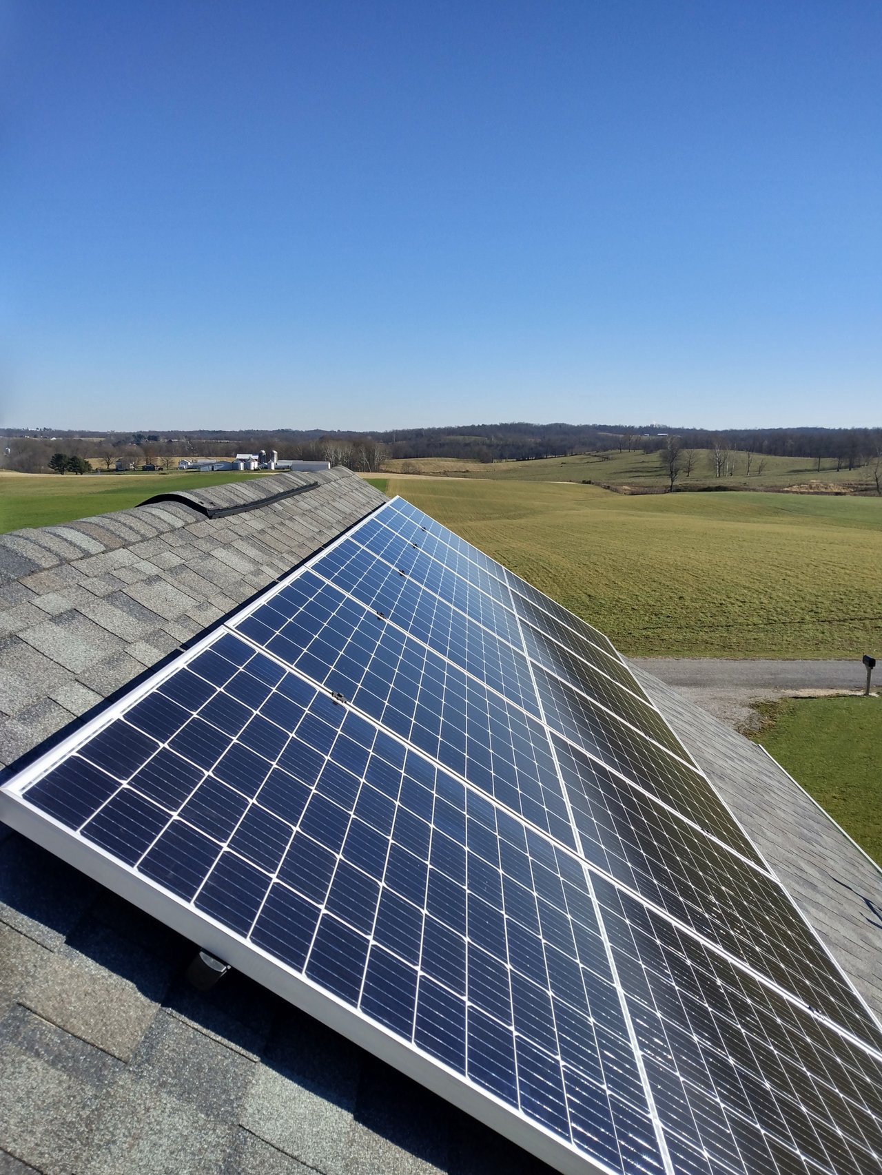 Solar panels on a roof overlooking rolling farm fields