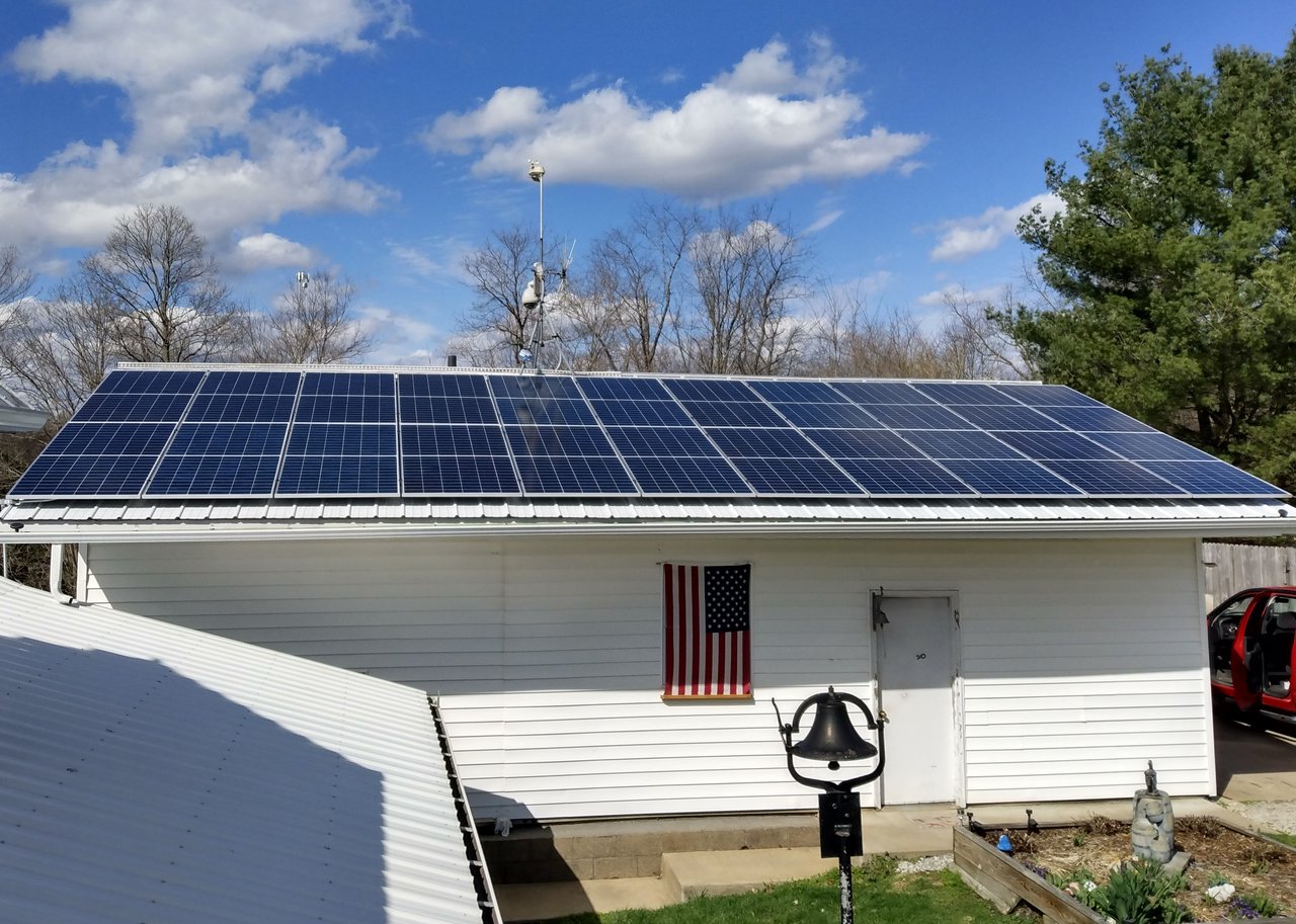 Solar panels on a white garage flying an American flag