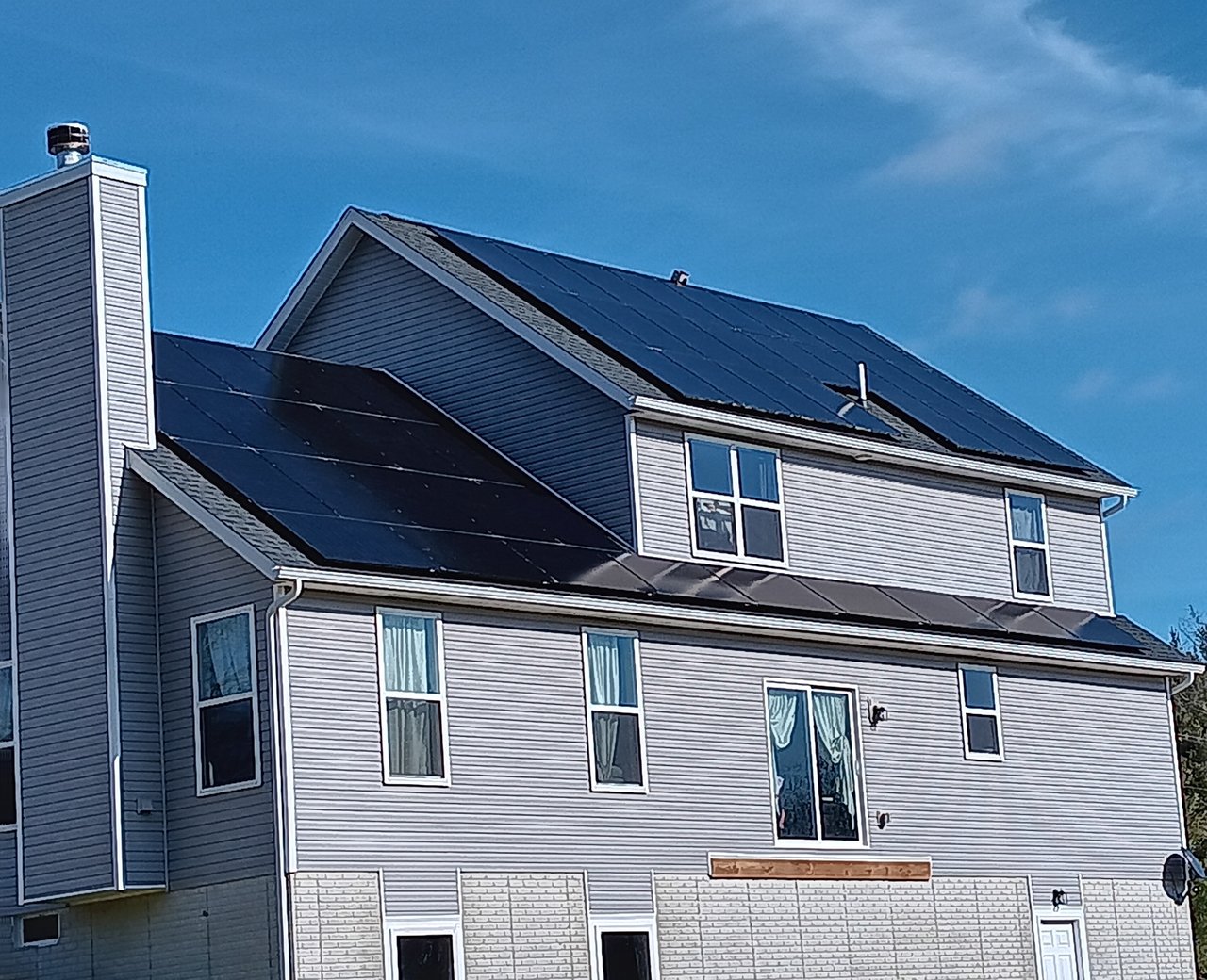 All-black solar panels on a gray two-story home in winter