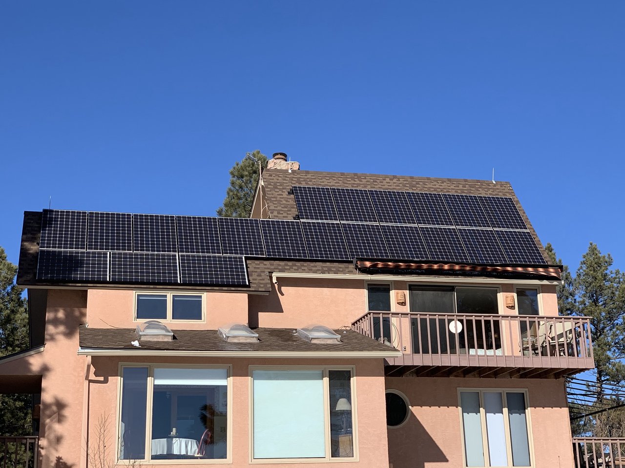 Solar panels on a stucco hillside home under a clear blue sky