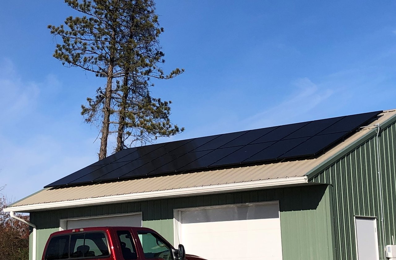 Black solar panels on a green metal pole barn