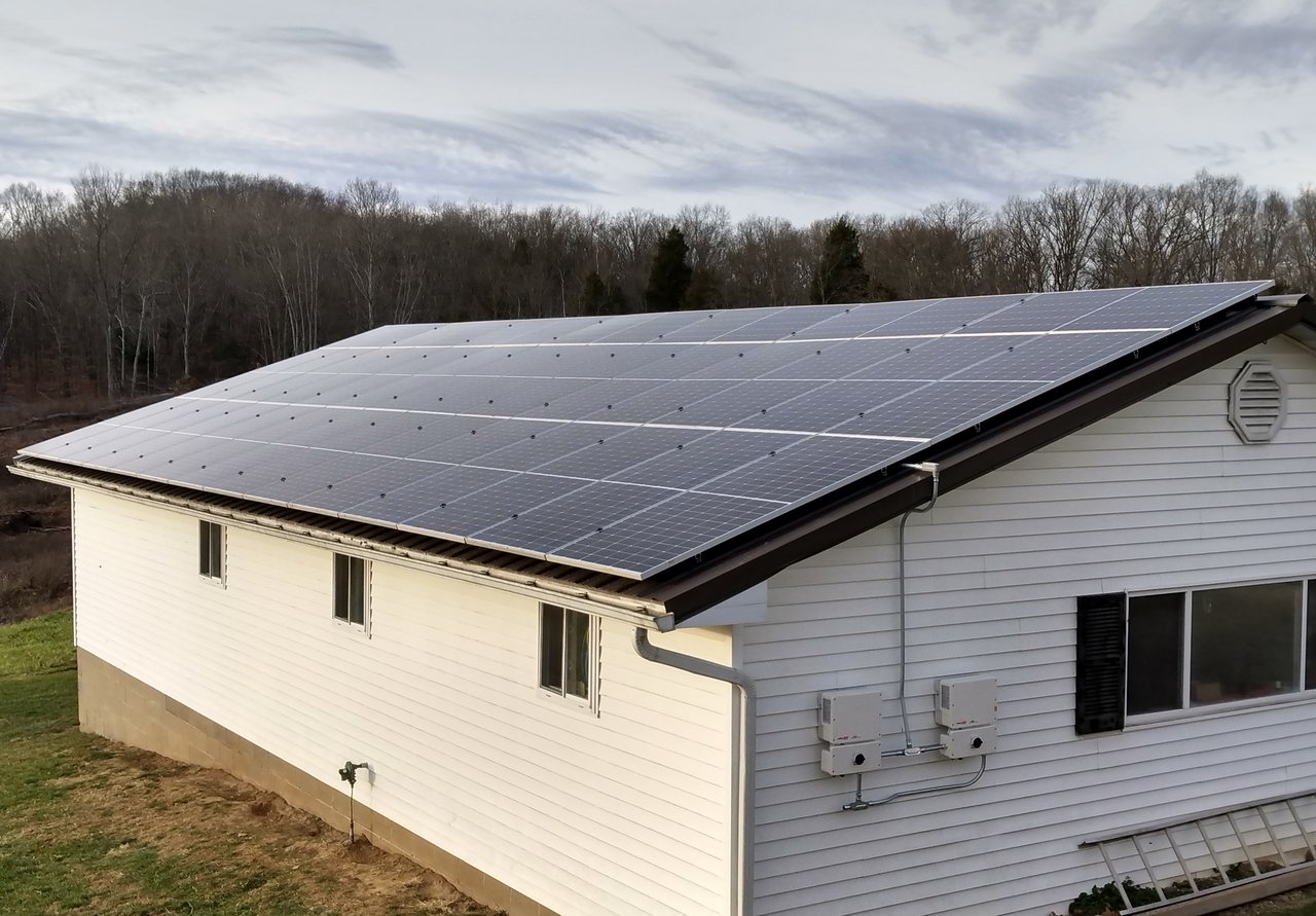 Black solar panels on a white ranch-style home